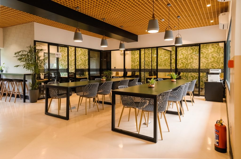 A modern and stylish workspace showcasing vibrant furniture, innovative ceiling design, comfortable seating areas, and appealing lighting fixtures.