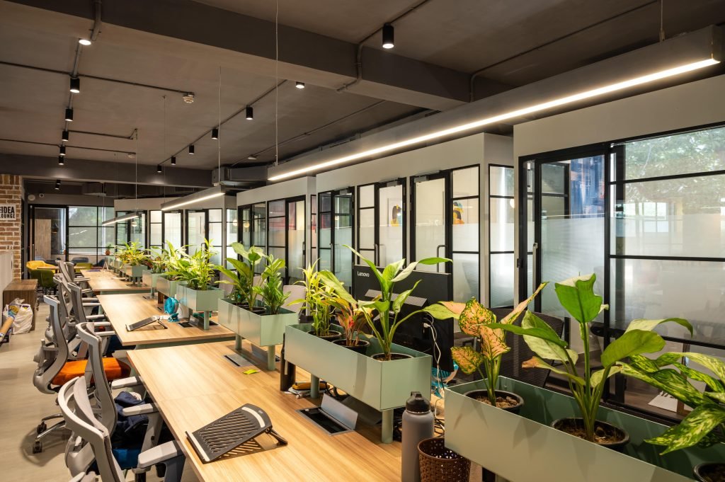 An innovative workspace featuring integrated office furniture designs with lush plants, ergonomic seating, and spacious, functional desks.