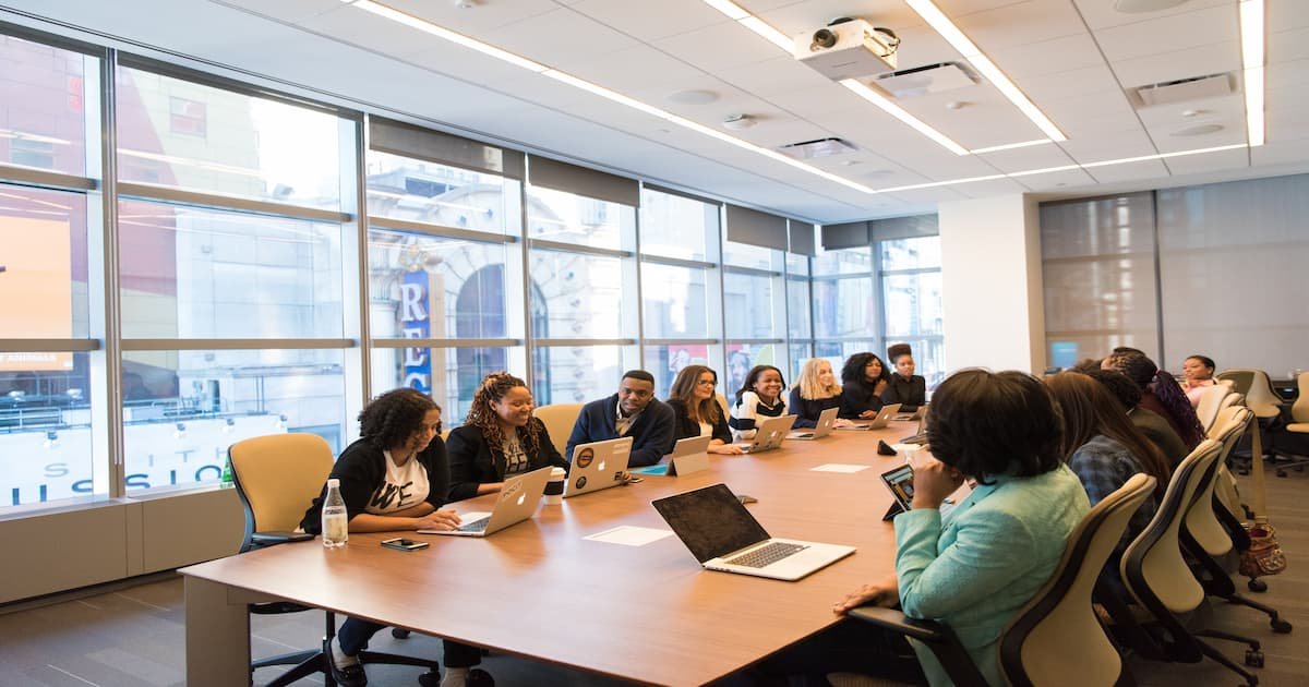 A diverse group of professionals collaborating in a modern conference room with large windows and natural lighting.